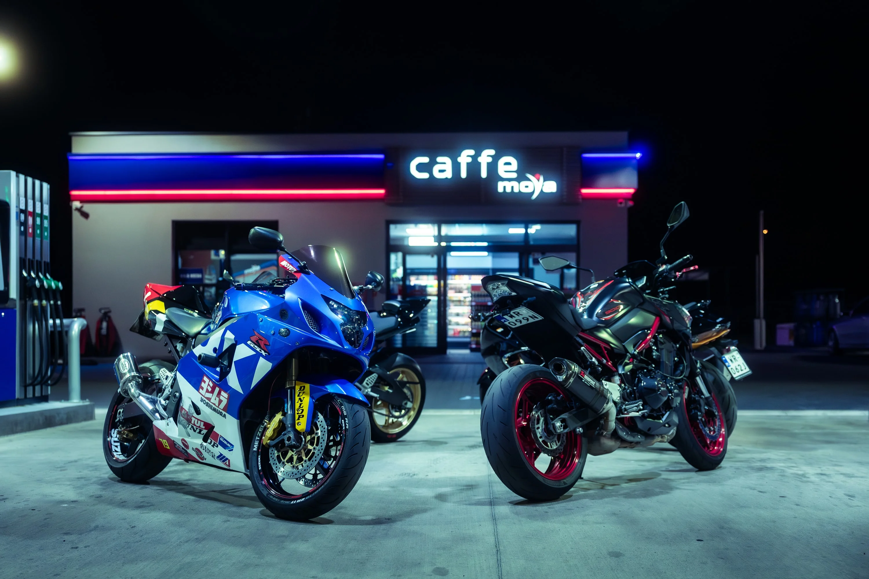 Dwa motocykle sportowe na stacji benzynowej nocą