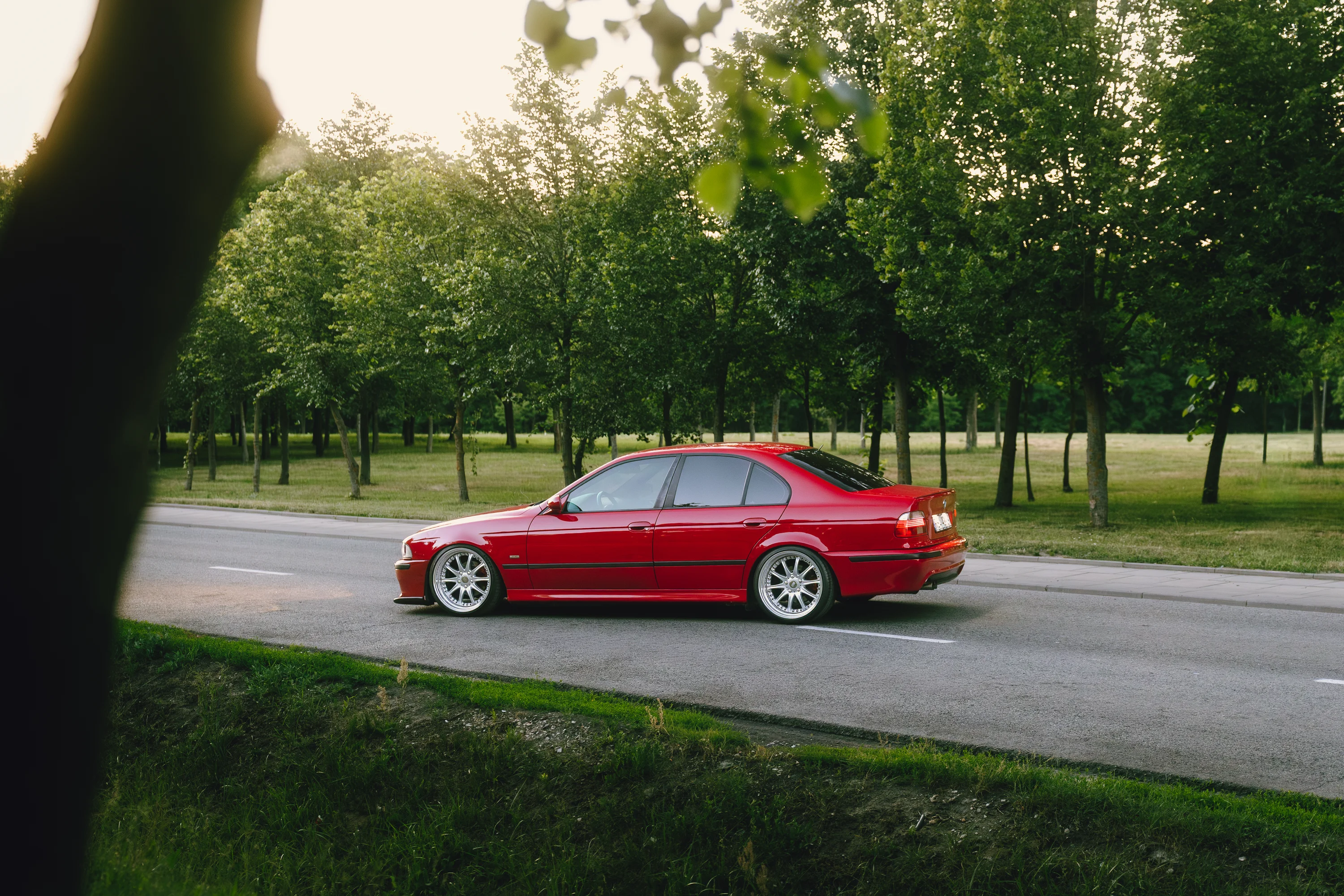 Czerwone BMW E39 na drodze w parku
