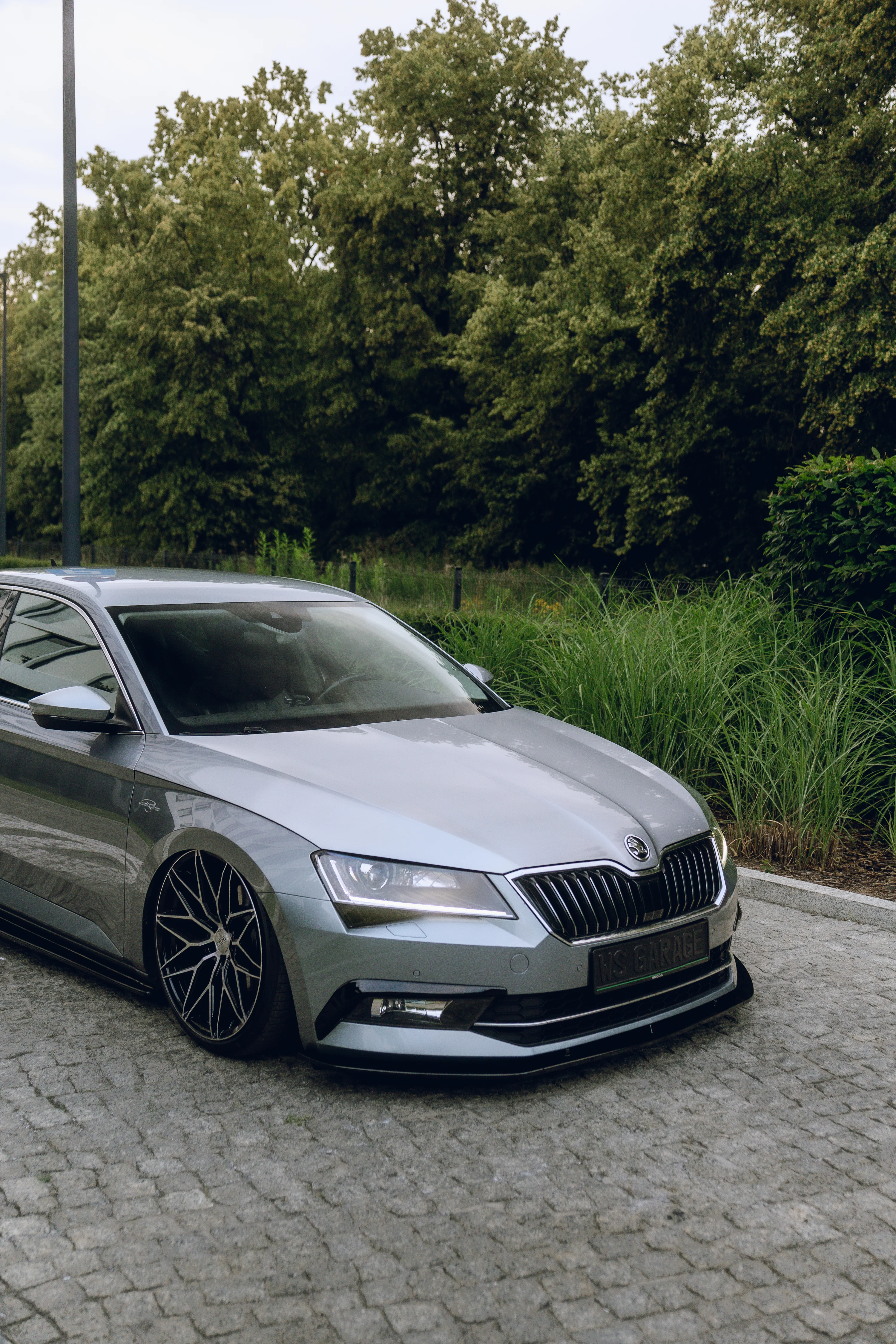 Škoda Superb na drodze przy drzewach