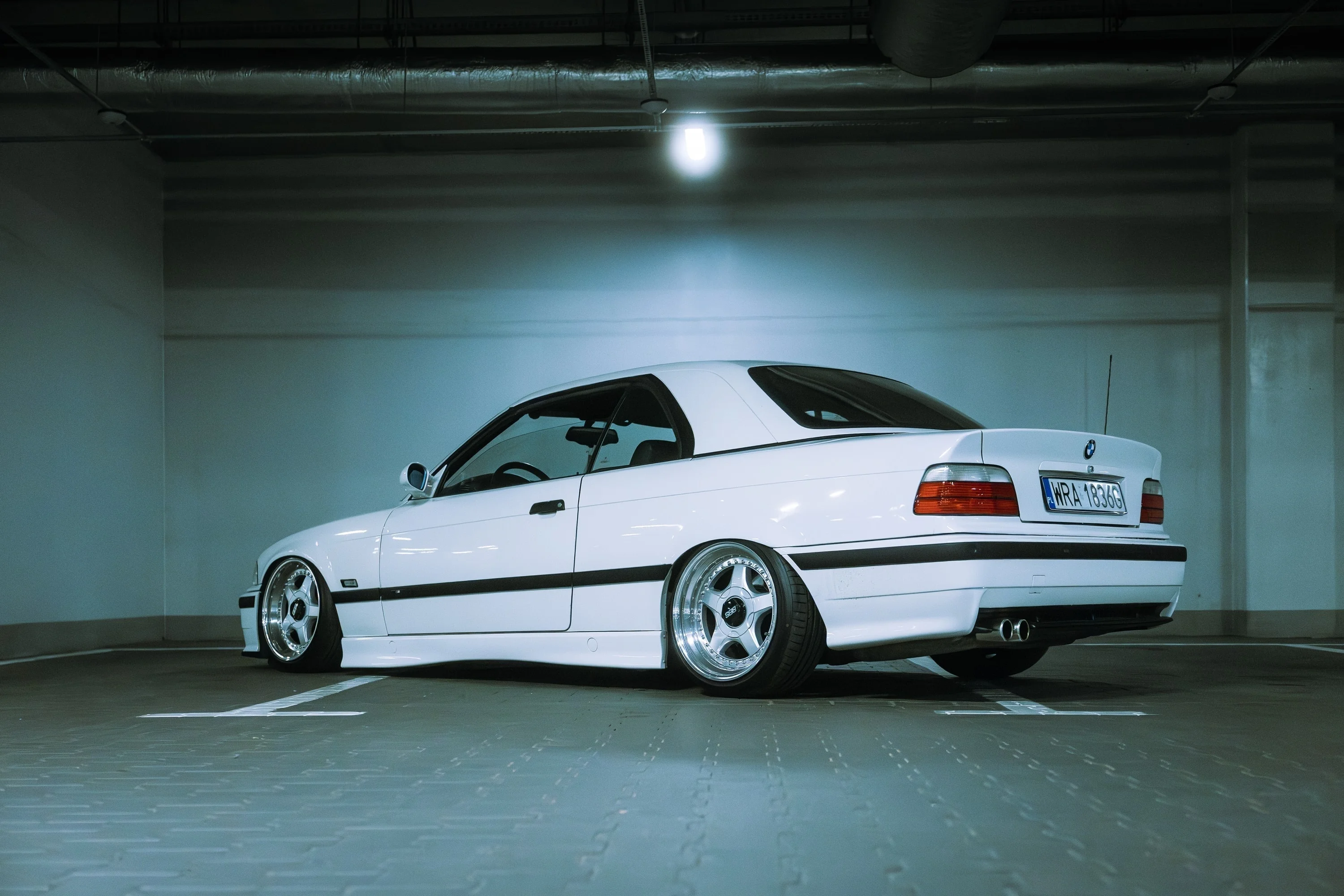 Białe BMW E36 na parkingu